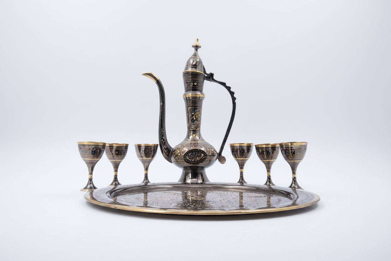 Decorative metal teapot set with tray and six cups on a white background