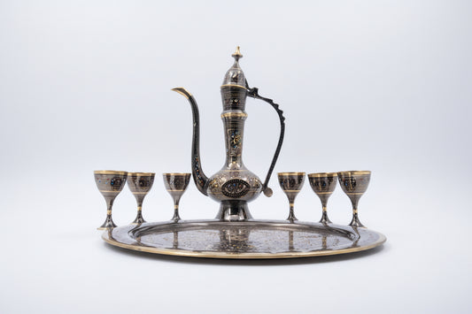 Decorative metal teapot set with tray and six cups on a white background